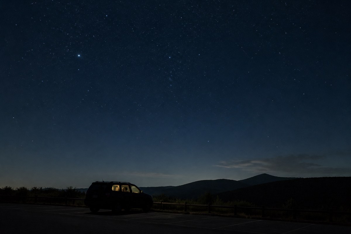高原の駐車場に停まった車と満天の星空