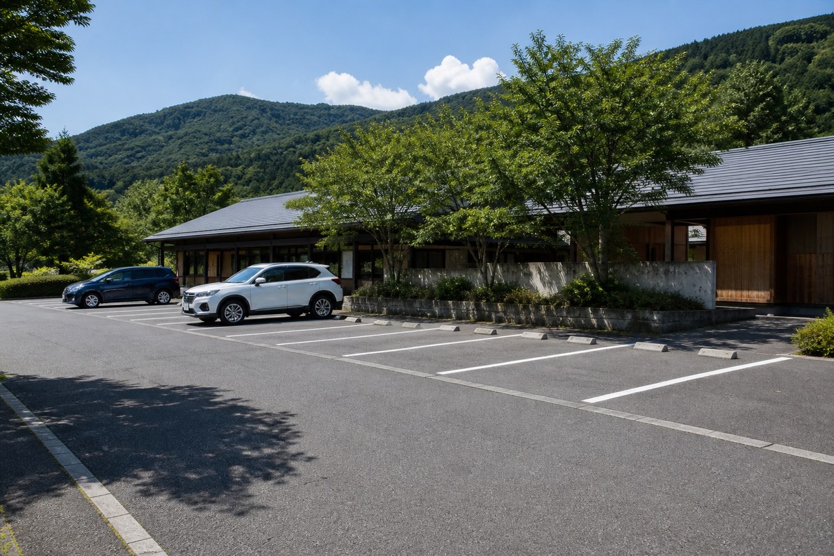 日中の道の駅の駐車場。区画線がはっきり引かれ、奥に低い建物と樹木がある