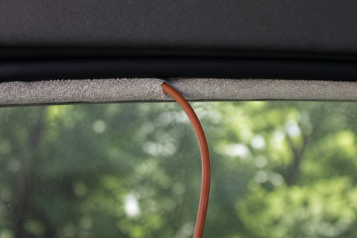 車内から見た窓の上部。ほぼ閉めたガラスとドア枠のあいだの隙間に丸めたタオルが詰められ、そこを延長コードが通って車内へ下りている